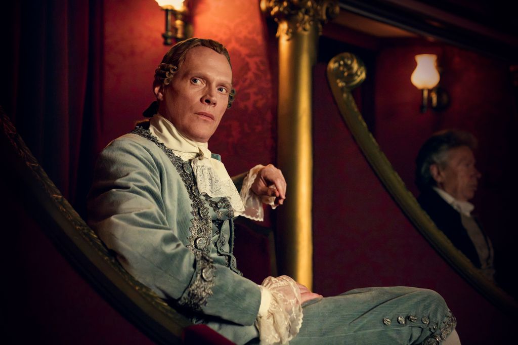man in period clothing sitting in theatre seat