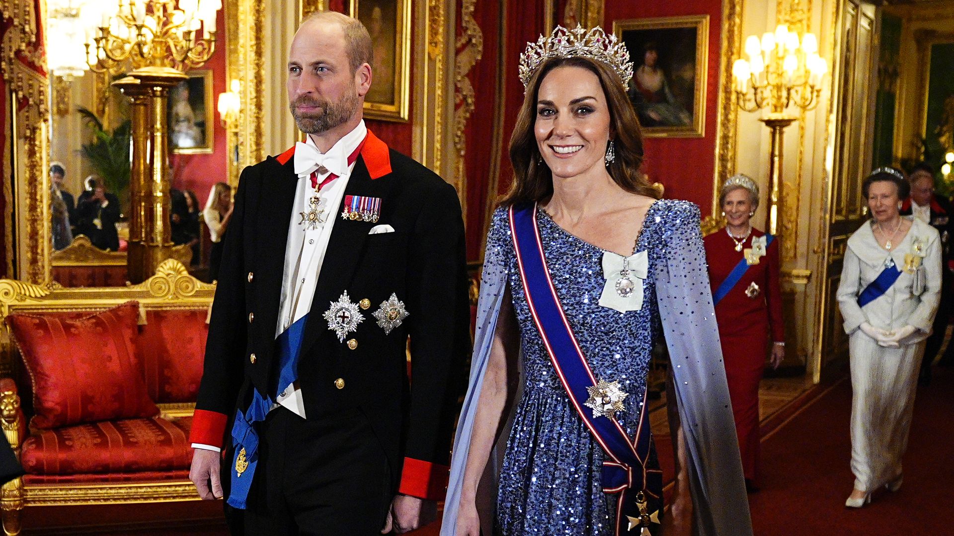 Prince William walking with Kate Middleton, the Duchess of Gloucester and Princess Anne are in the background